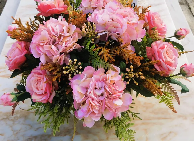 Pormenor de arranjo artificial com hortênsias, rosas cor-de-rosa e folhagem de outono
