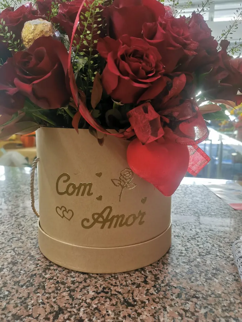 Flower box redonda em cartão kraft com a inscrição Com Amor, cheia de rosas vermelhas