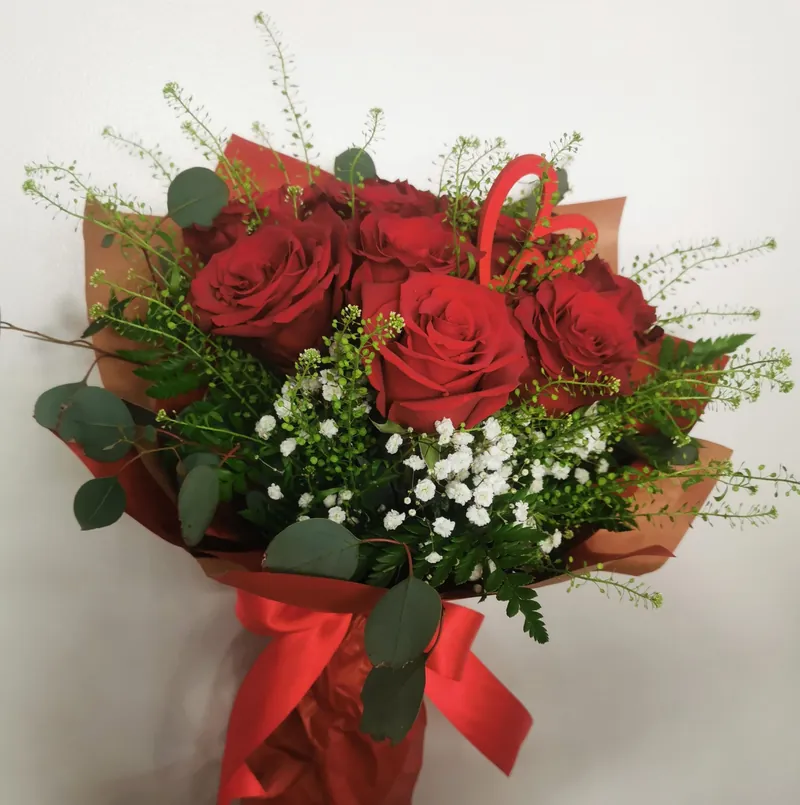 Ramo de rosas vermelhas com gipsófila e eucalipto, embrulhado em papel kraft com laço vermelho
